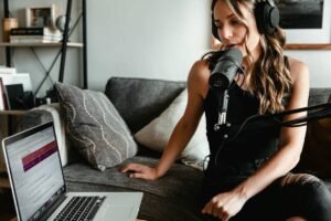 Woman recording a podcast with a microphone and laptop. 