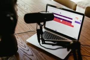 Laptop displaying audio editing software with a microphone in front. 